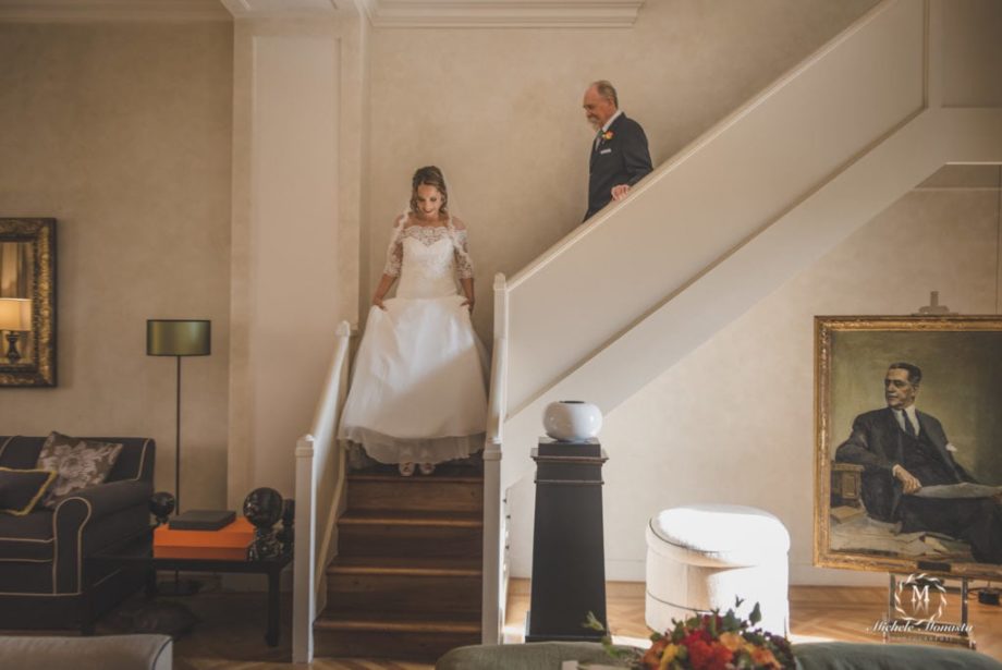 sposa scende le scale col padre pronta per il giorno del suo matrimonio in toscana