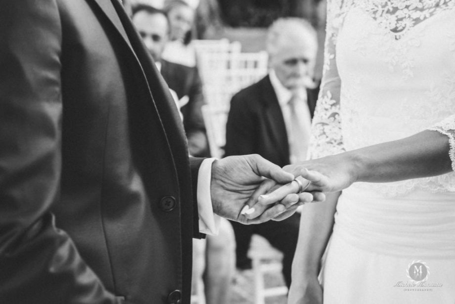particolare della mano dello sposo che tiene la mano della sposa con l'anello di matrimonio