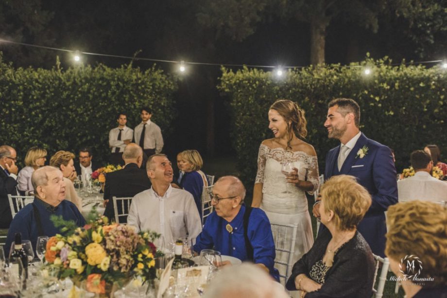 La sposa e lo sposo fra i tavoli la sera del loro matrimonio a Villa Nozzole in Toscana