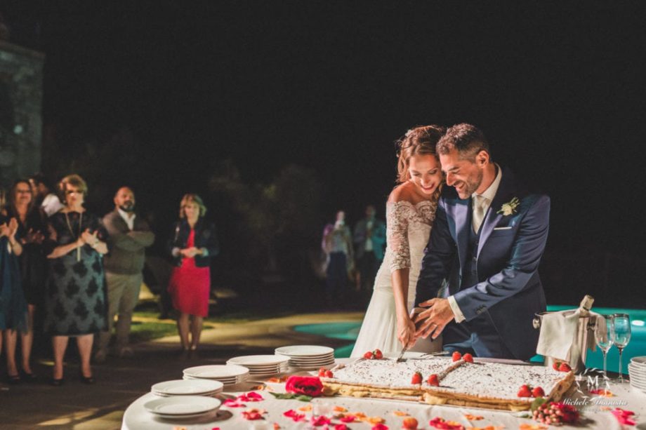 Sposi sorridenti durante il taglio della torta in un matrimonio toscano